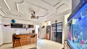 Una hall d'albergo con reception, un'area bar in legno, un grande acquario e un soffitto decorativo.