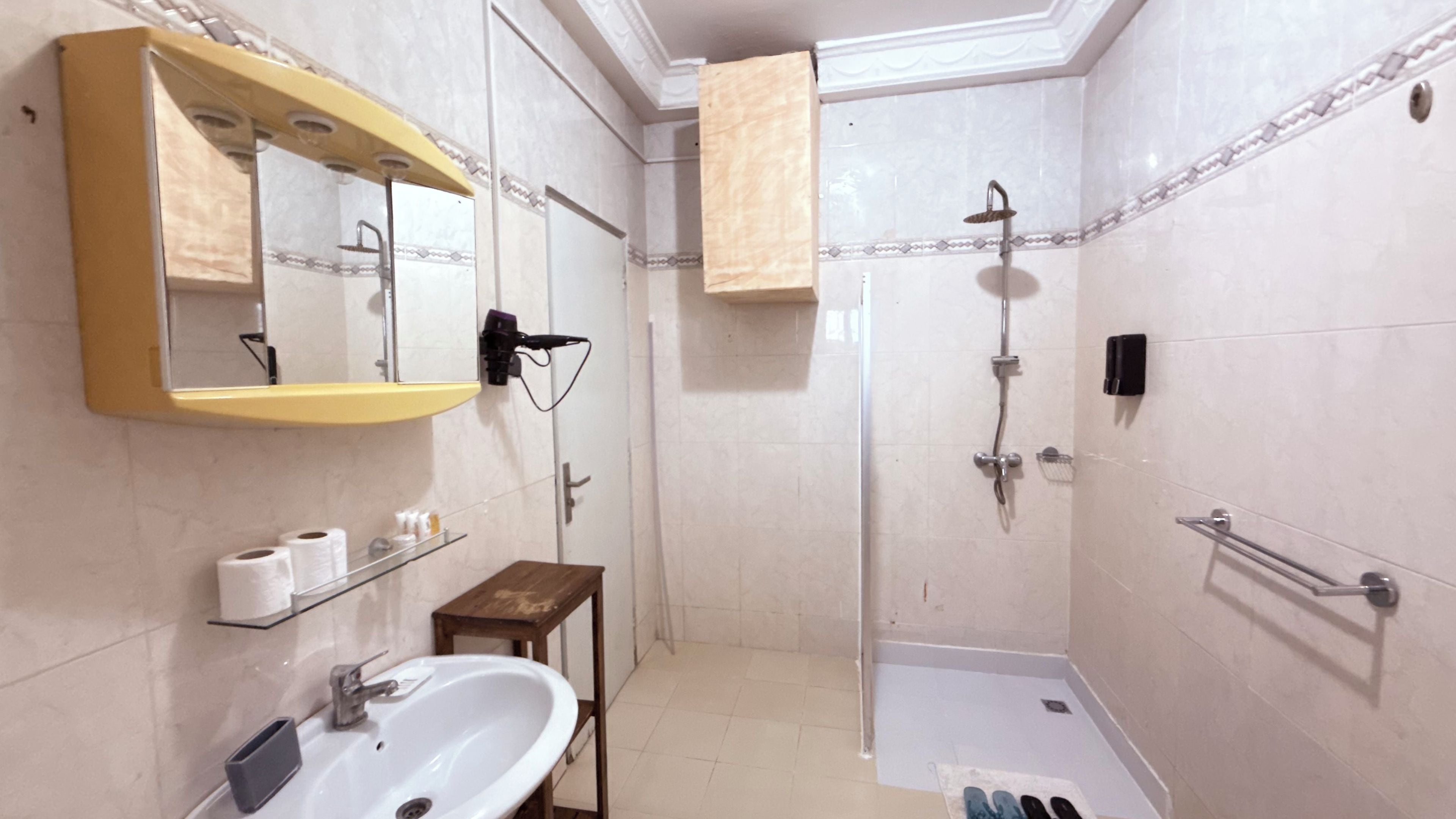 A bathroom with a sink, mirror, toilet, shower, and towel rack.