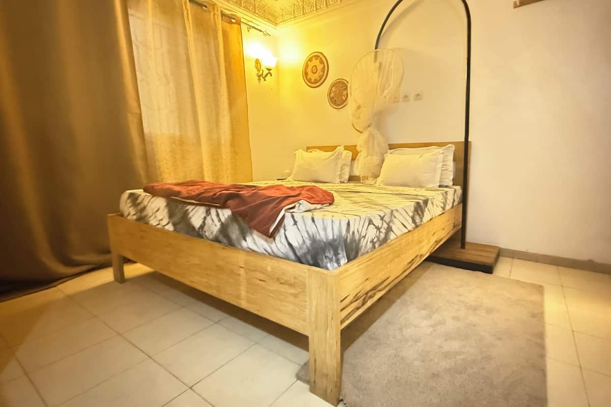 A wooden bed with a blanket, white pillows, and a canopy.