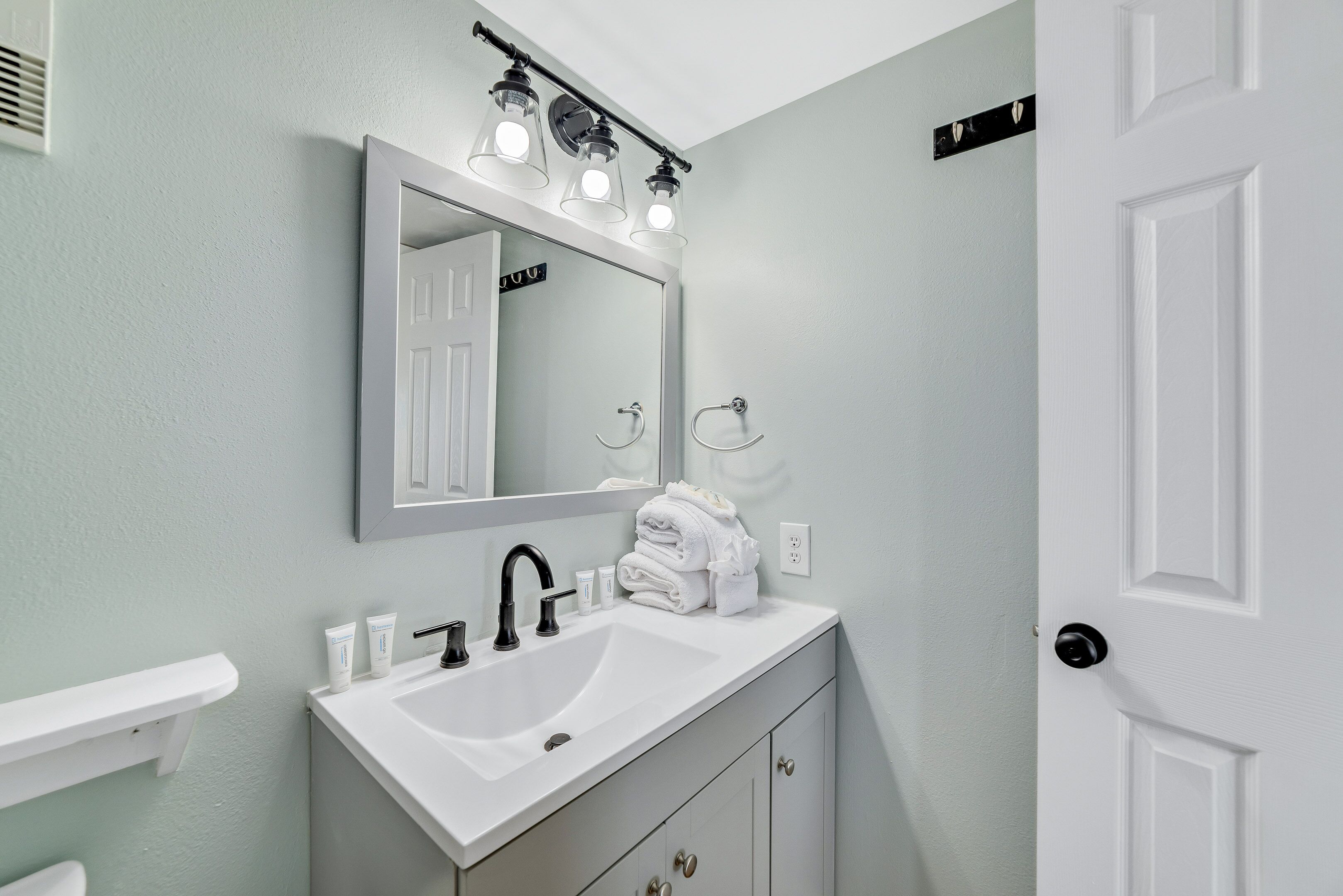 A bathroom with a white sink, mirror, and towel rack.