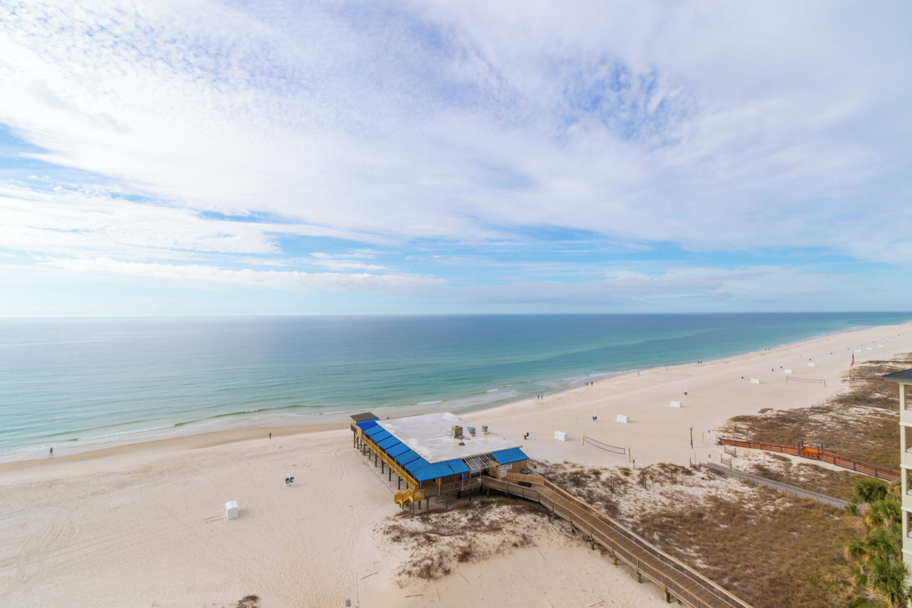 A beach with a pier and a building with a blue roof.