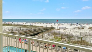 A beach view from a balcony with a pool, wooden deck, and beach access. - Boardwalk Condos by Hosteeva (Gulf Shores)