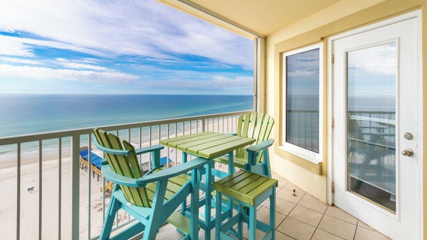 A balcony with a view of the ocean, featuring a table and chairs. - Boardwalk Condos by Hosteeva (Gulf Shores)