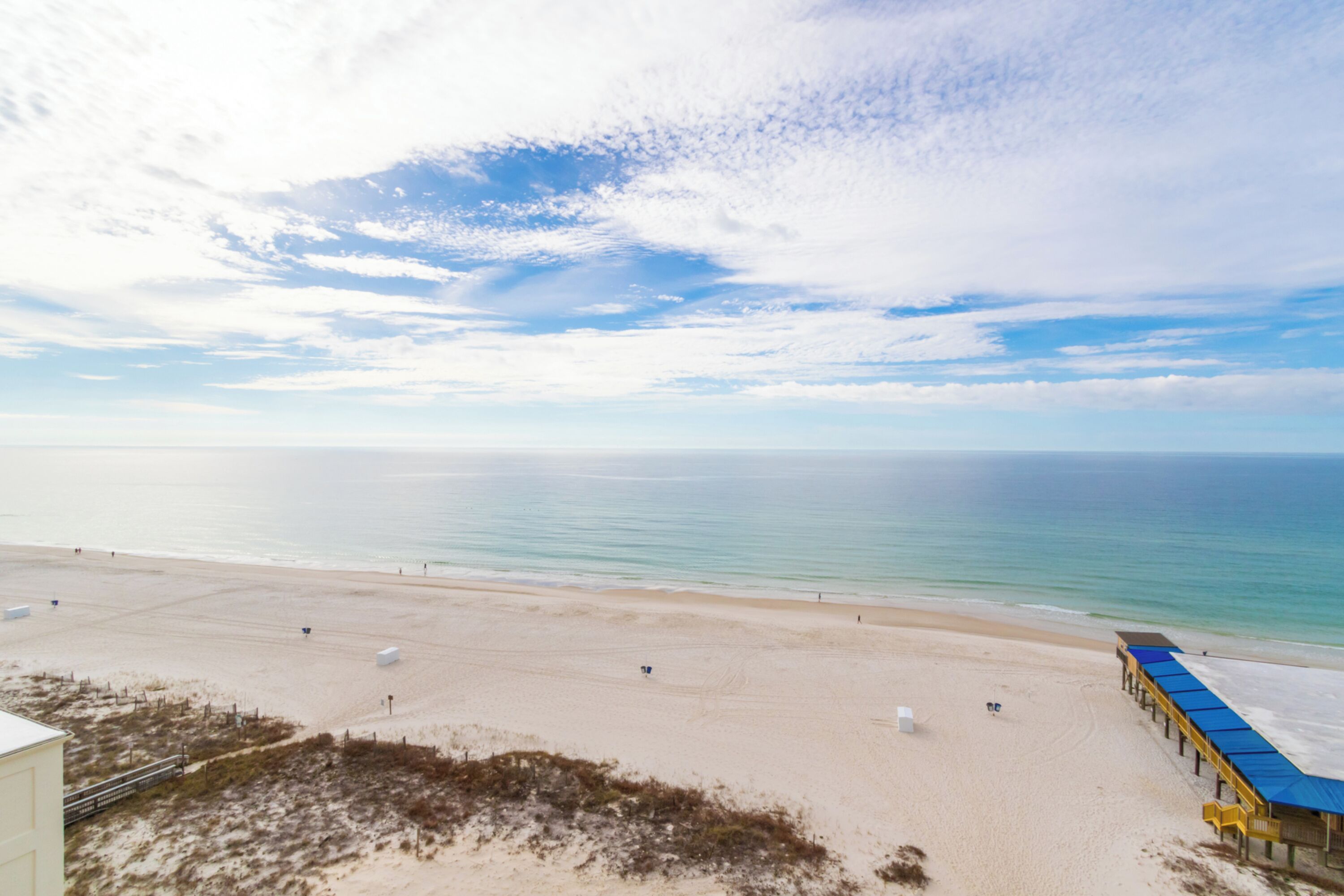 A beach with a sandy shore and a building with a blue roof.
