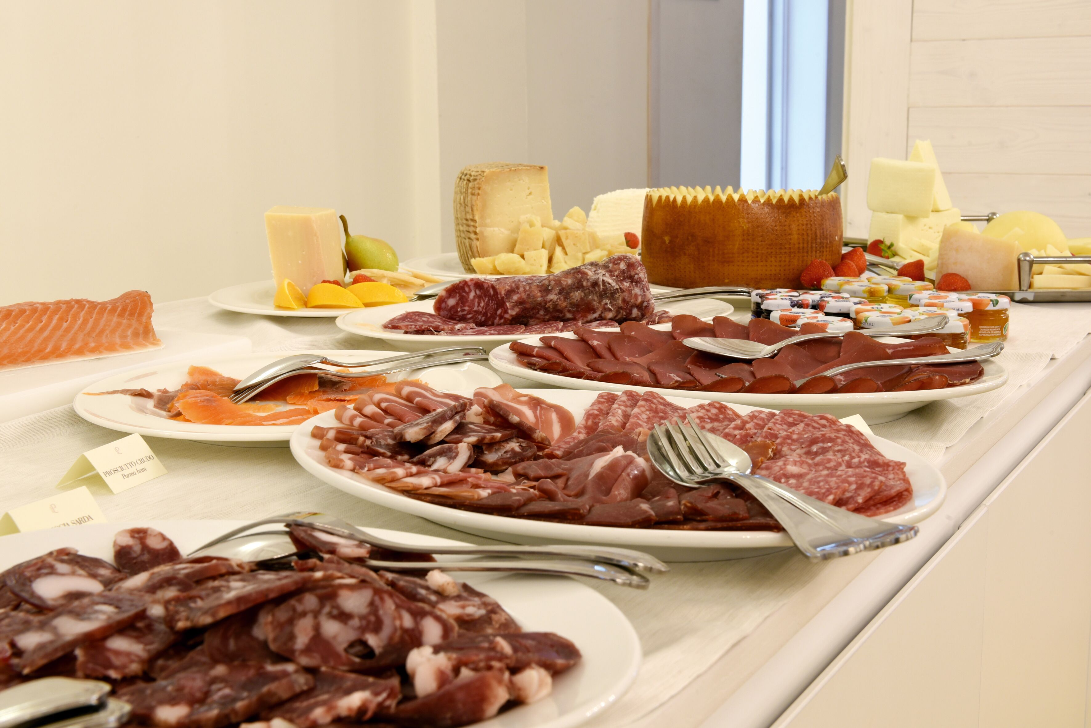 A buffet with various meats, cheeses, and fruits.