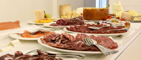 A buffet with various meats, cheeses, and fruits.