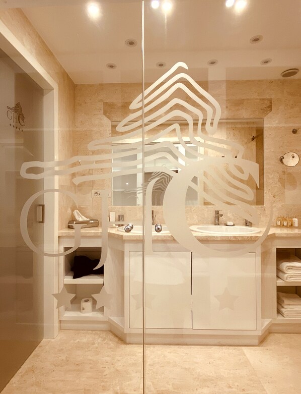 Un baño moderno con mampara de vidrio, un lavabo y un espejo.