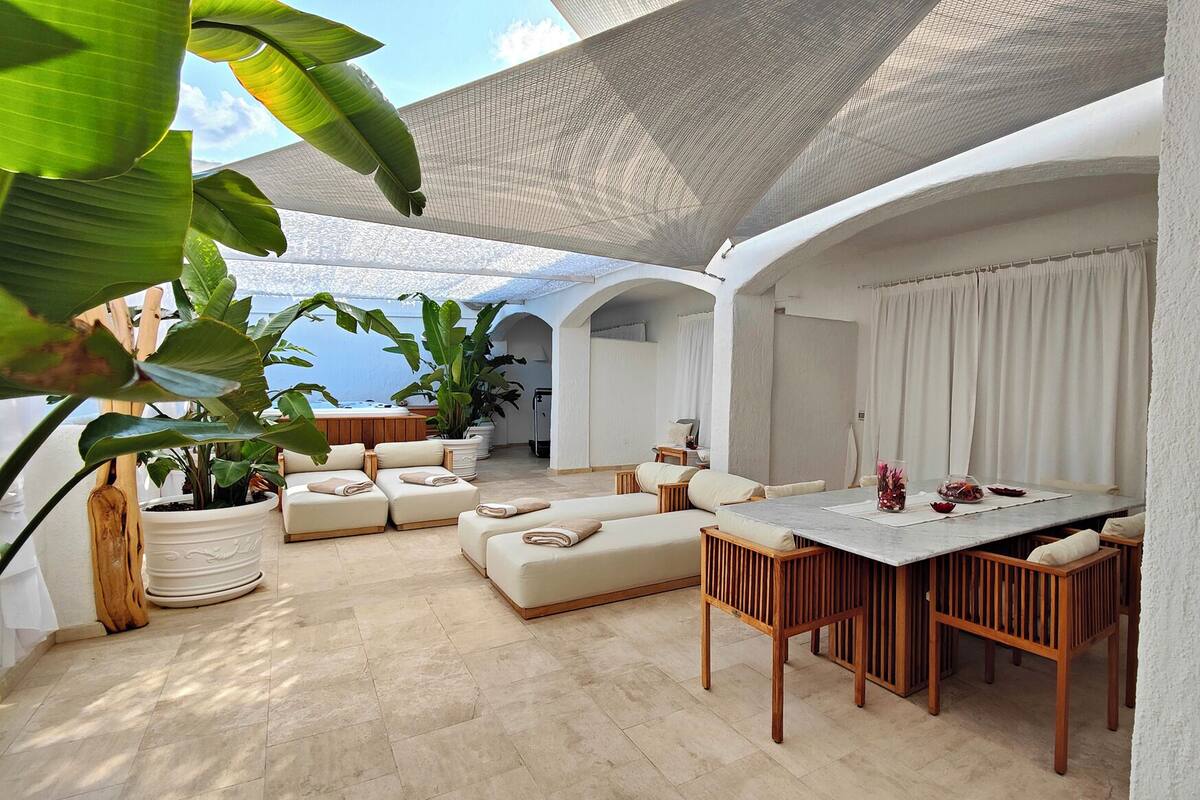 A spacious outdoor living area with a pool, seating arrangements, and potted plants.