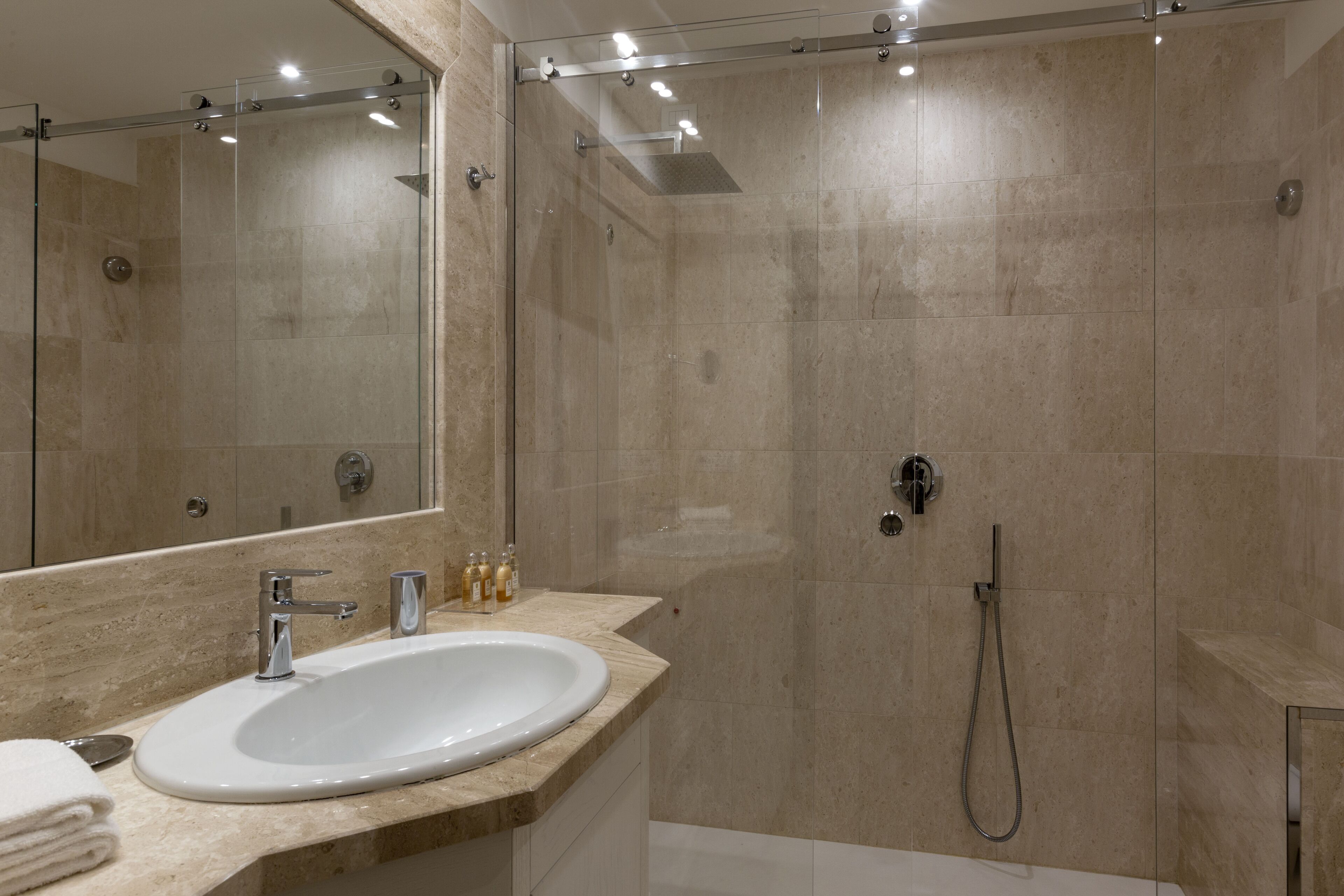 Une salle de bain moderne avec un grand miroir, un lavabo et un espace douche.