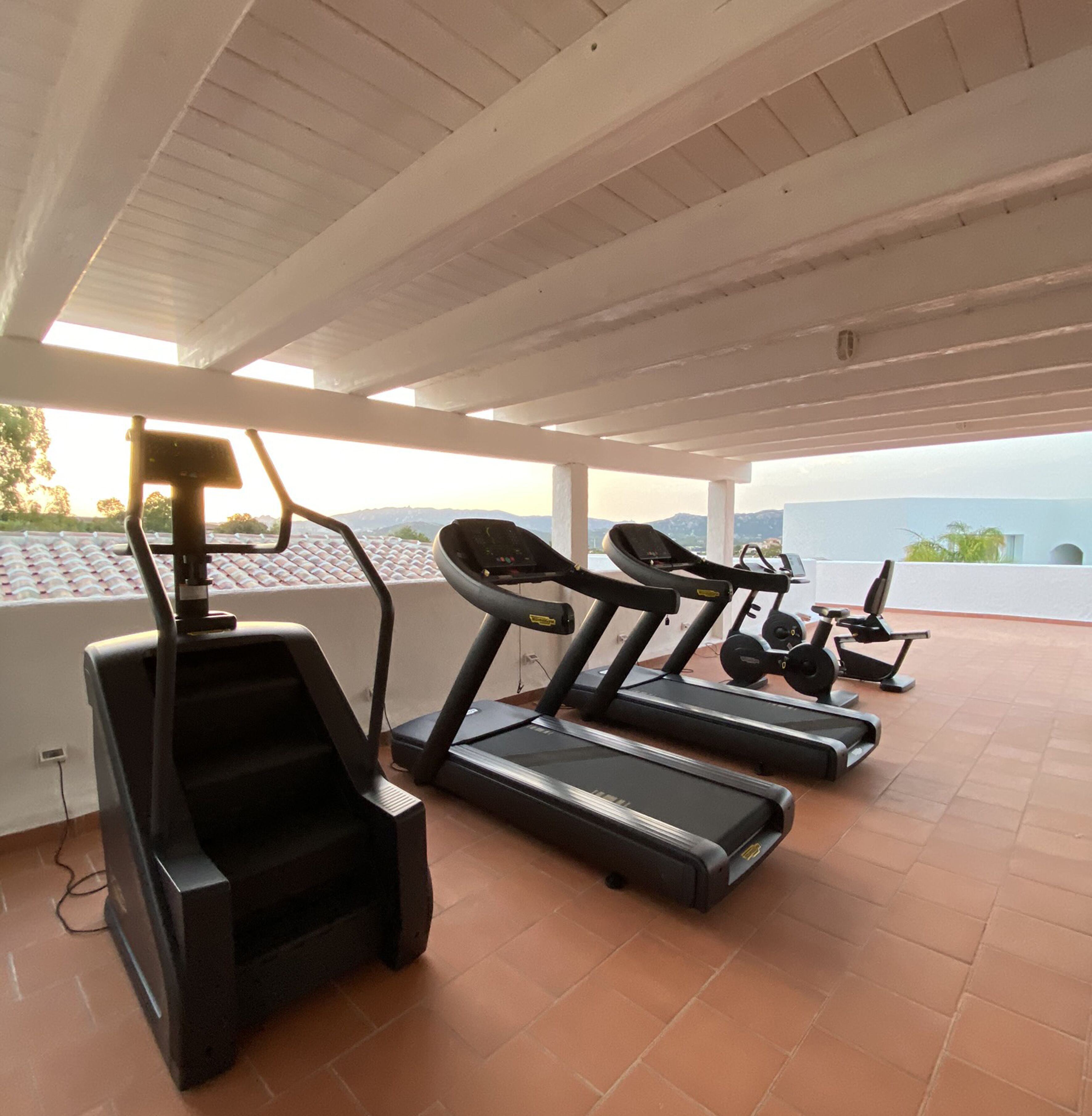 A covered outdoor gym area with treadmills and a stair climber.