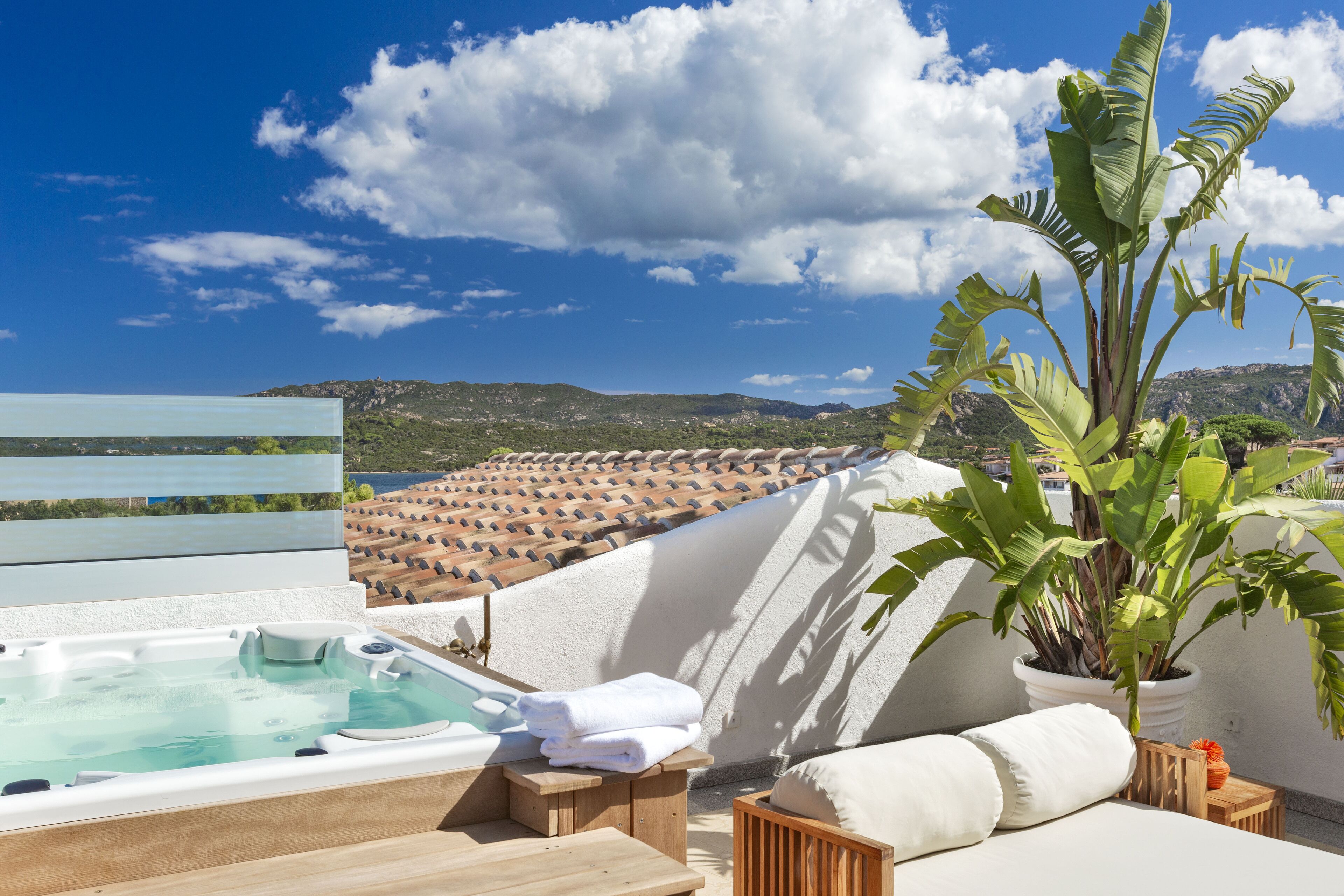 Eine Dachterrasse mit Whirlpool, Sitzgelegenheit und Blumentöpfen.