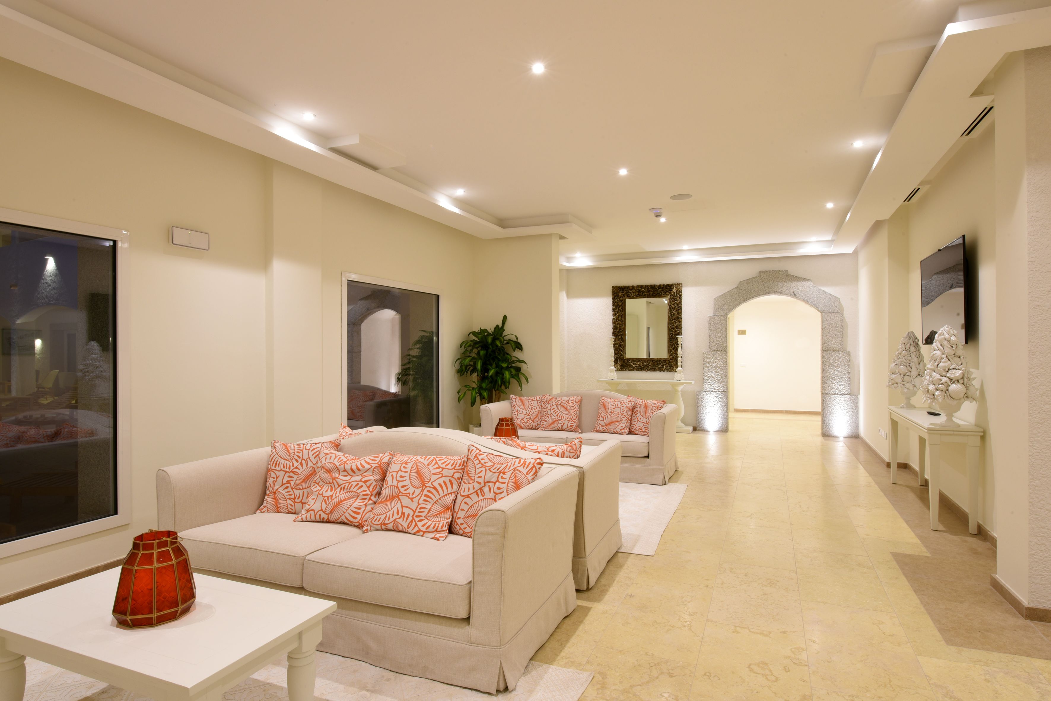 Un salon spacieux avec un canapé beige, une table basse blanche et une grande fenêtre.