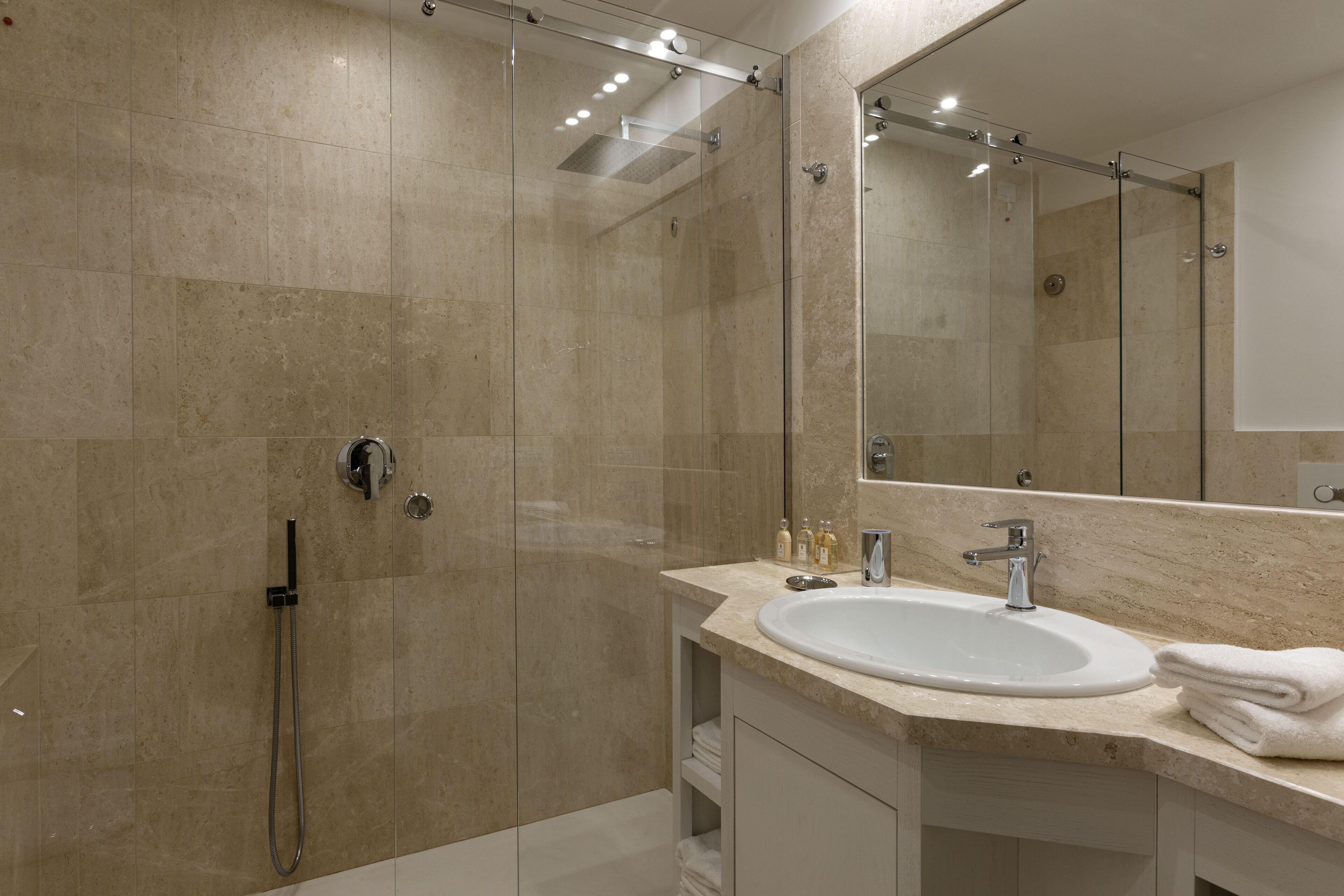 A modern bathroom with a glass-enclosed shower, a sink, and a large mirror.