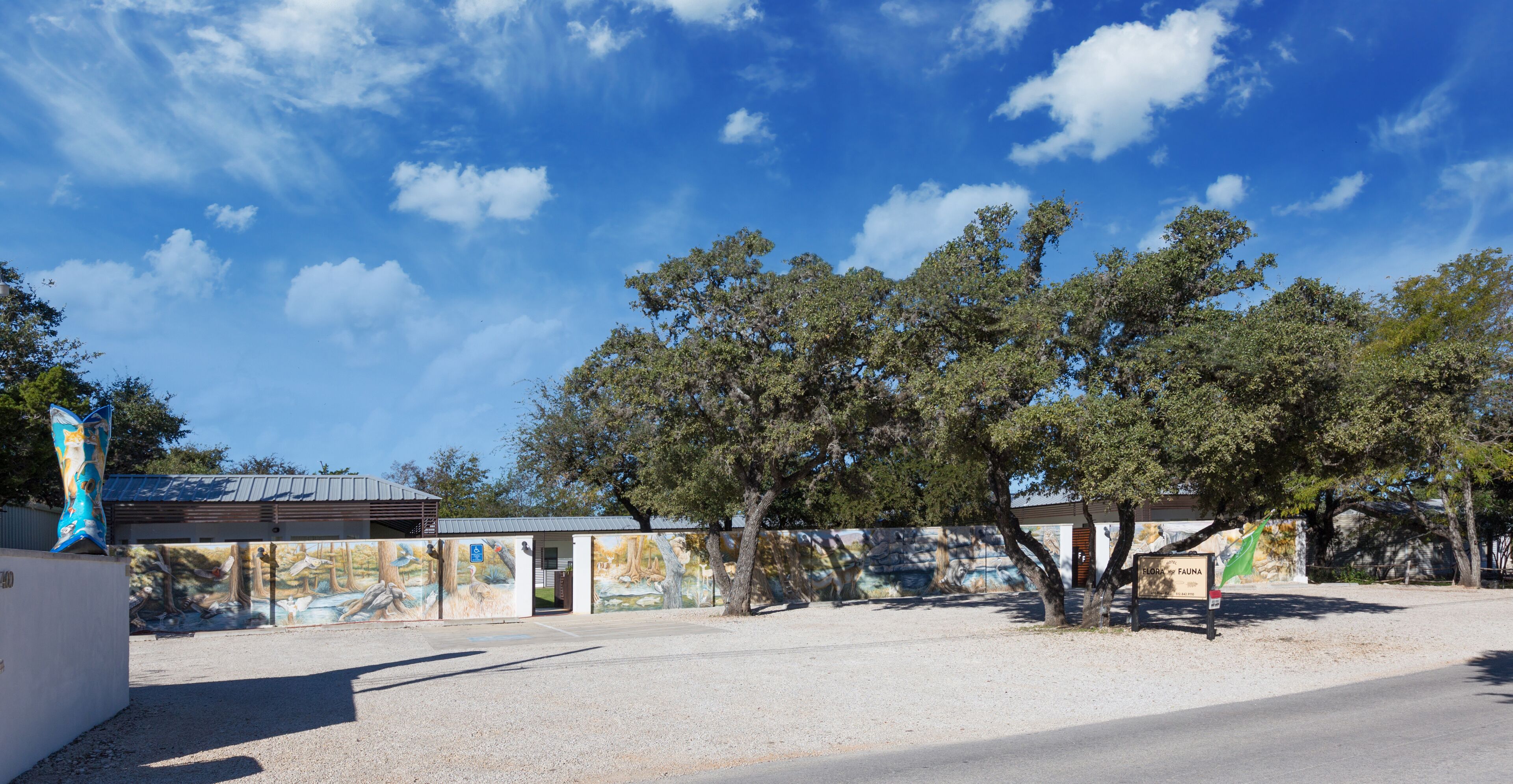 A building with a mural on the side, a parking lot, and a clear blue sky.