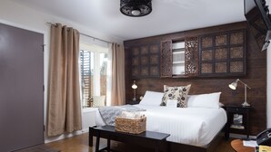 A modern bedroom with a large bed, bedside tables, a desk, and a window with curtains. - Hotel Flora & Fauna (Wimberley)