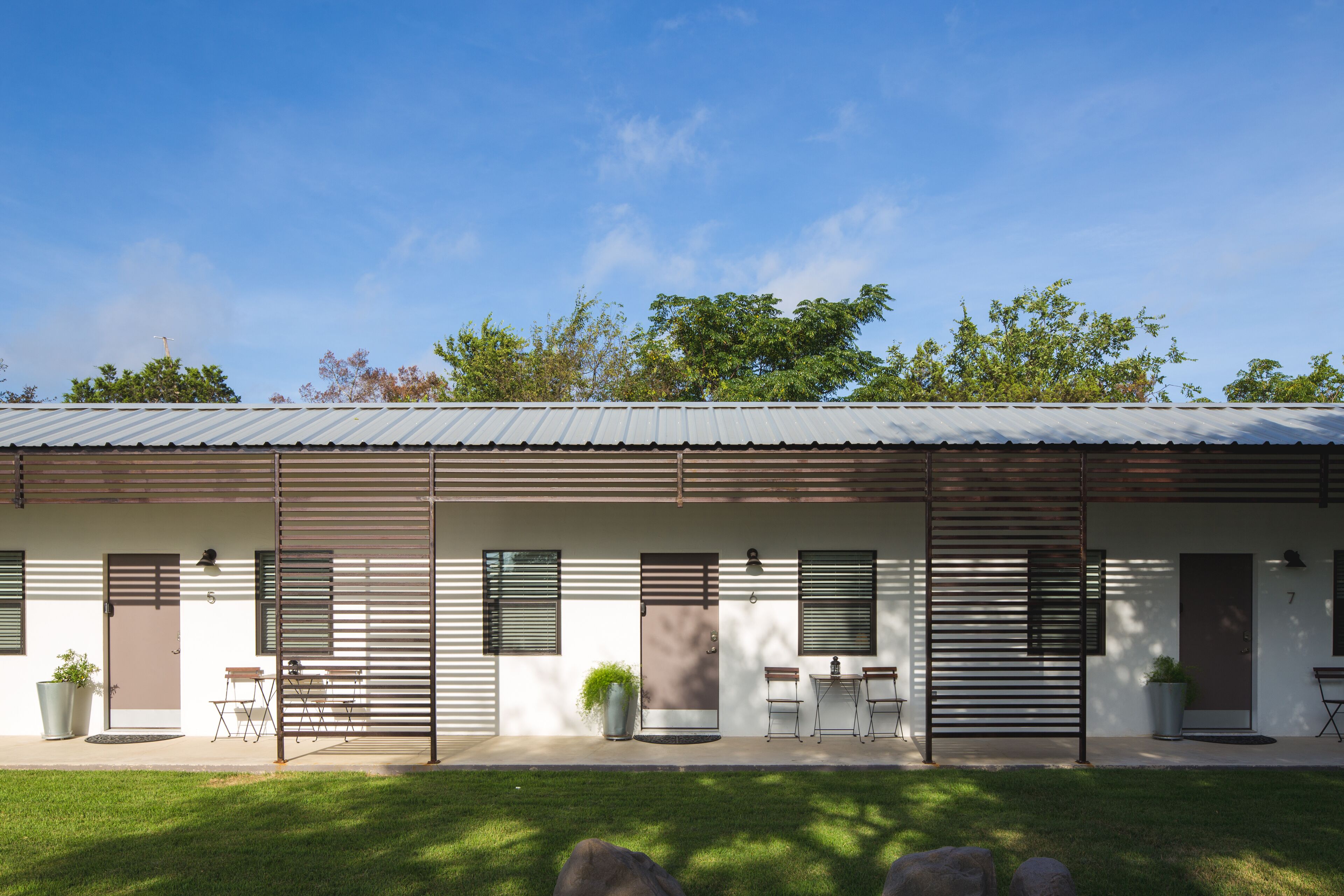 A modern building with a flat roof, large windows, and a well-maintained lawn.