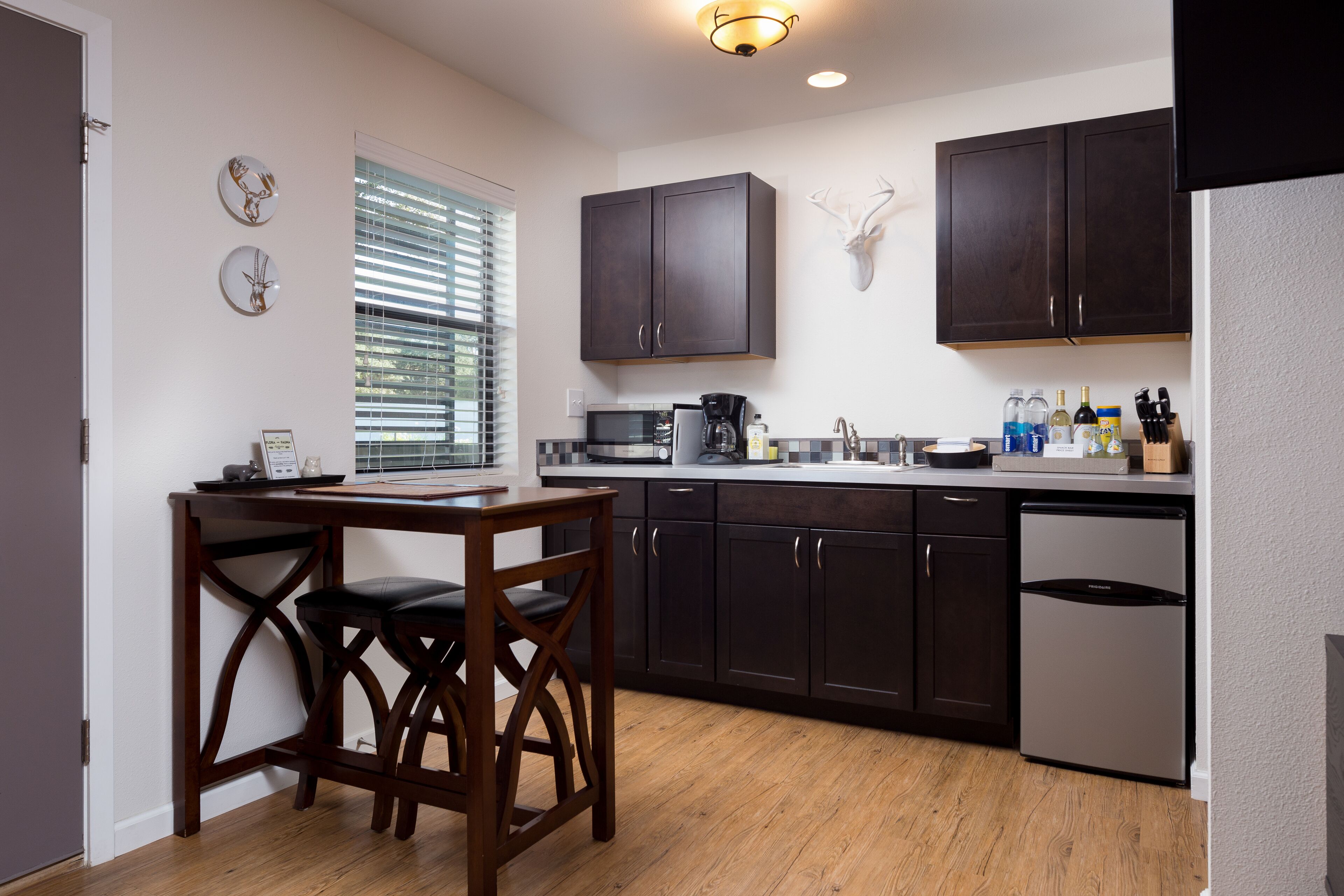 A modern kitchen with dark wooden cabinets, a built-in microwave, and a stainless steel dishwasher.