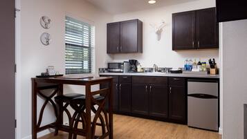 A modern kitchen with dark wooden cabinets, a built-in microwave, and a stainless steel dishwasher.