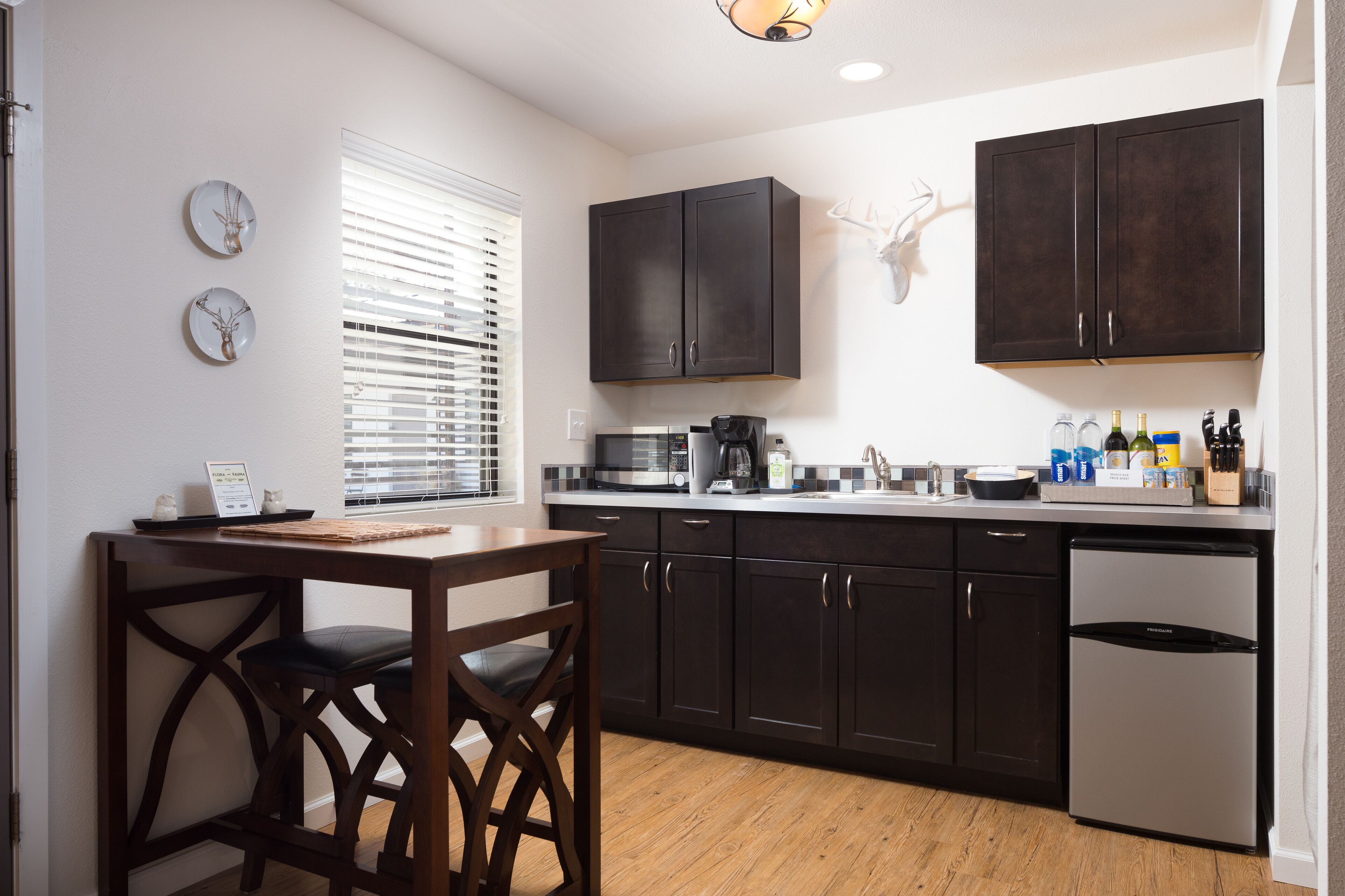 A modern kitchen with dark cabinets, a microwave, a coffee maker, and a refrigerator.