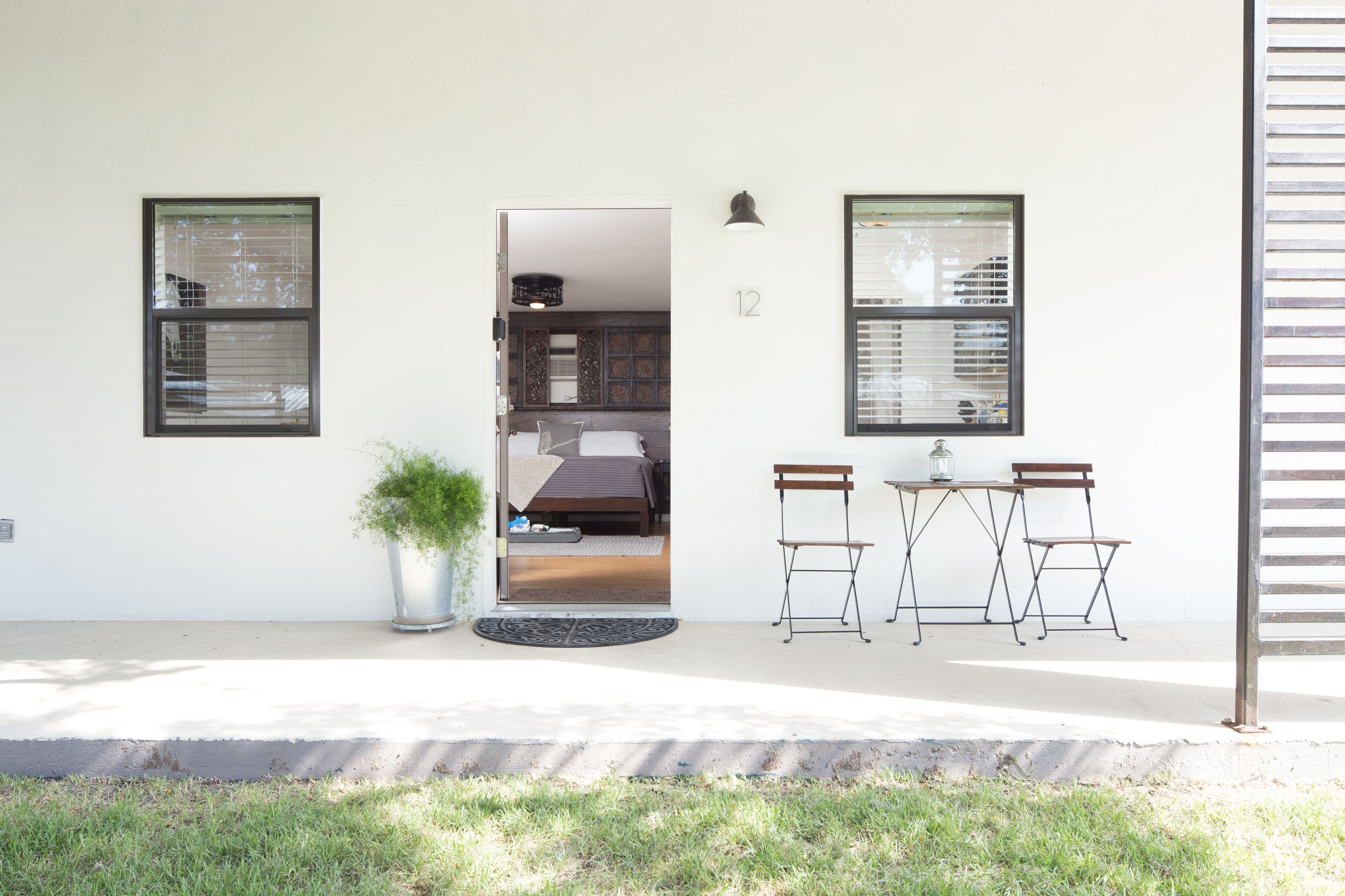 A modern house with a dining area, a potted plant, and a number 12 on the wall.