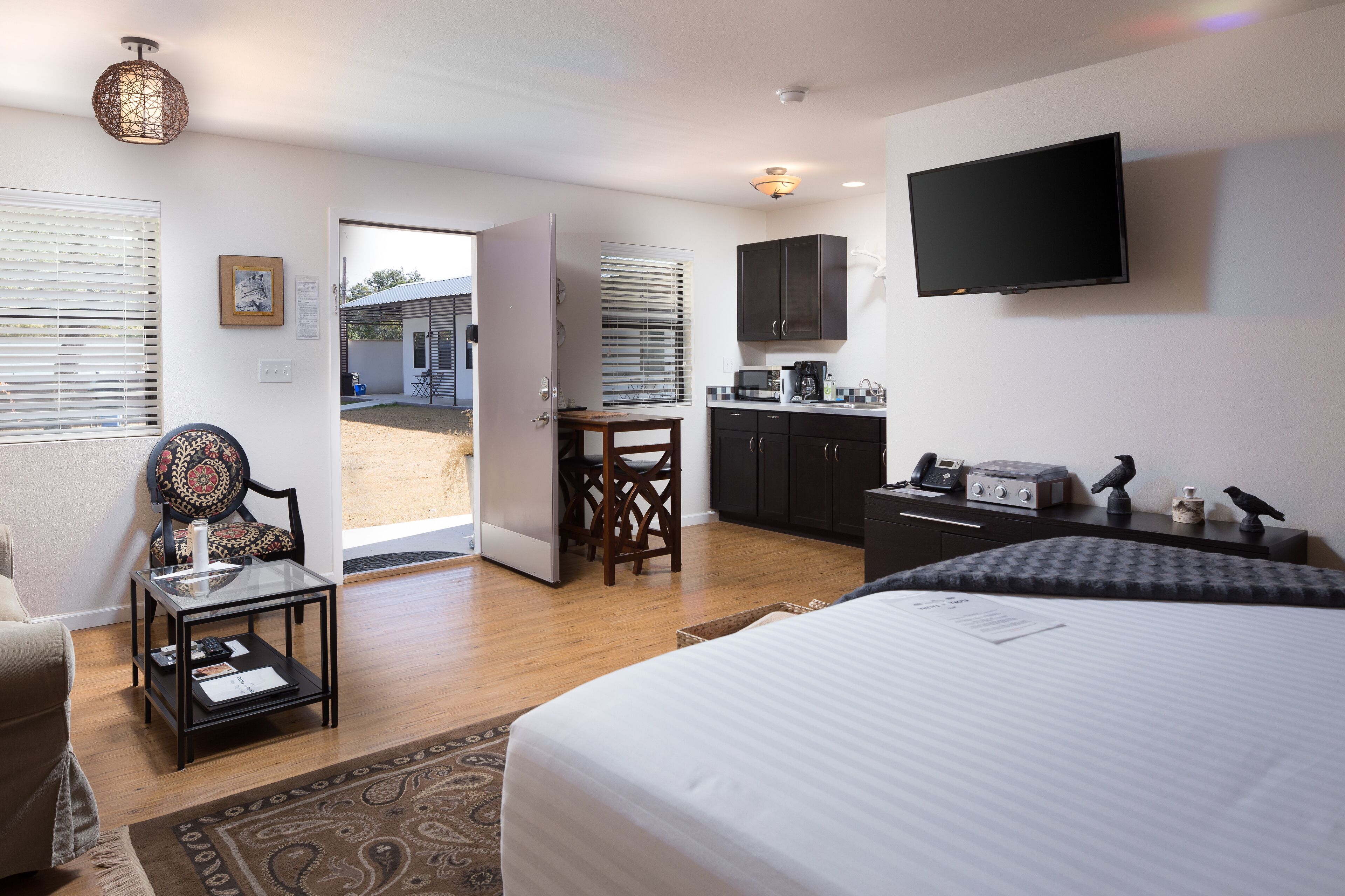 A hotel room with a bed, a desk, a chair, a television, and a view of the outside.
