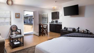 A hotel room with a bed, a desk, a chair, a television, and a view of the outside.