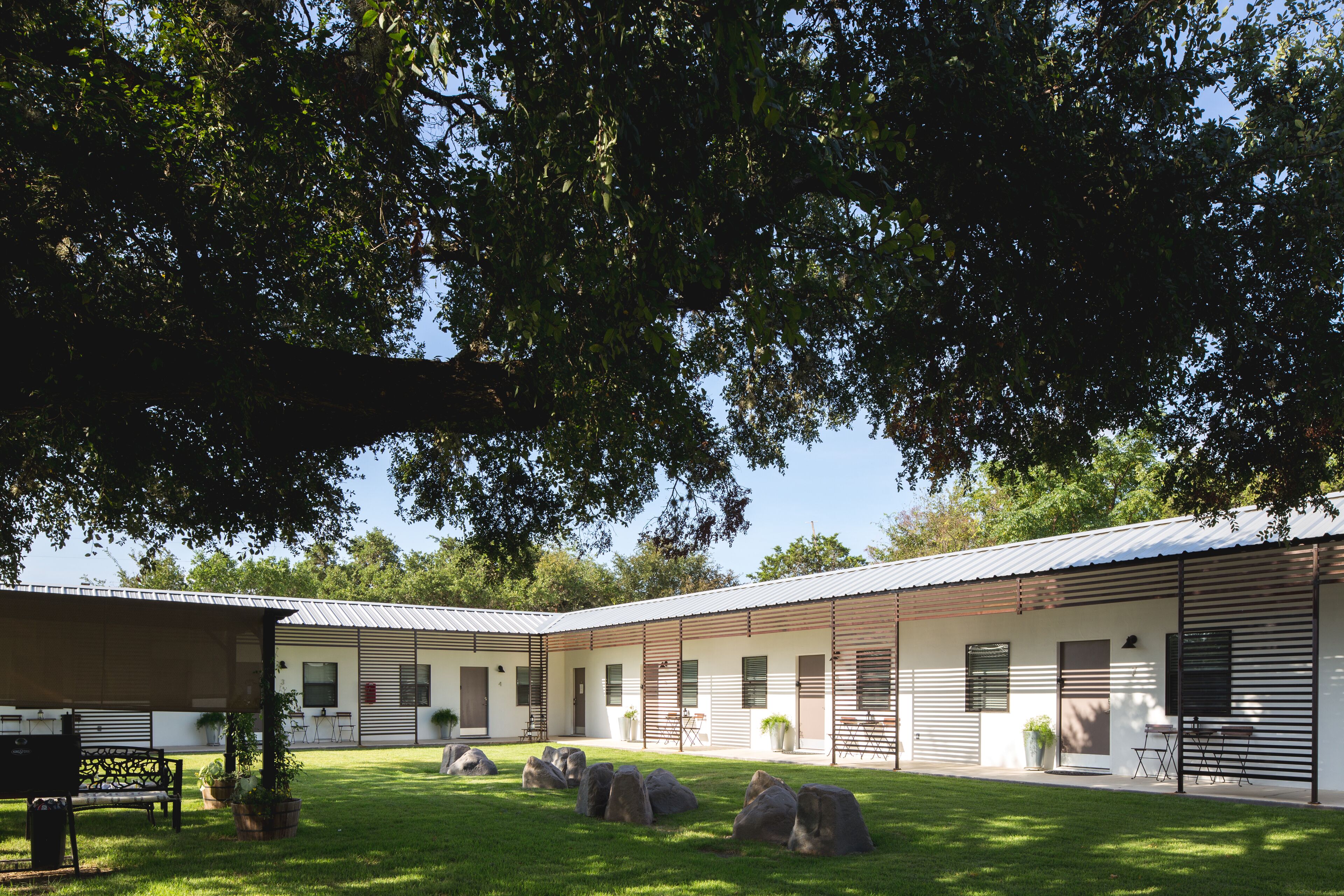 A modern building with a covered outdoor area, large rocks, and a bench.