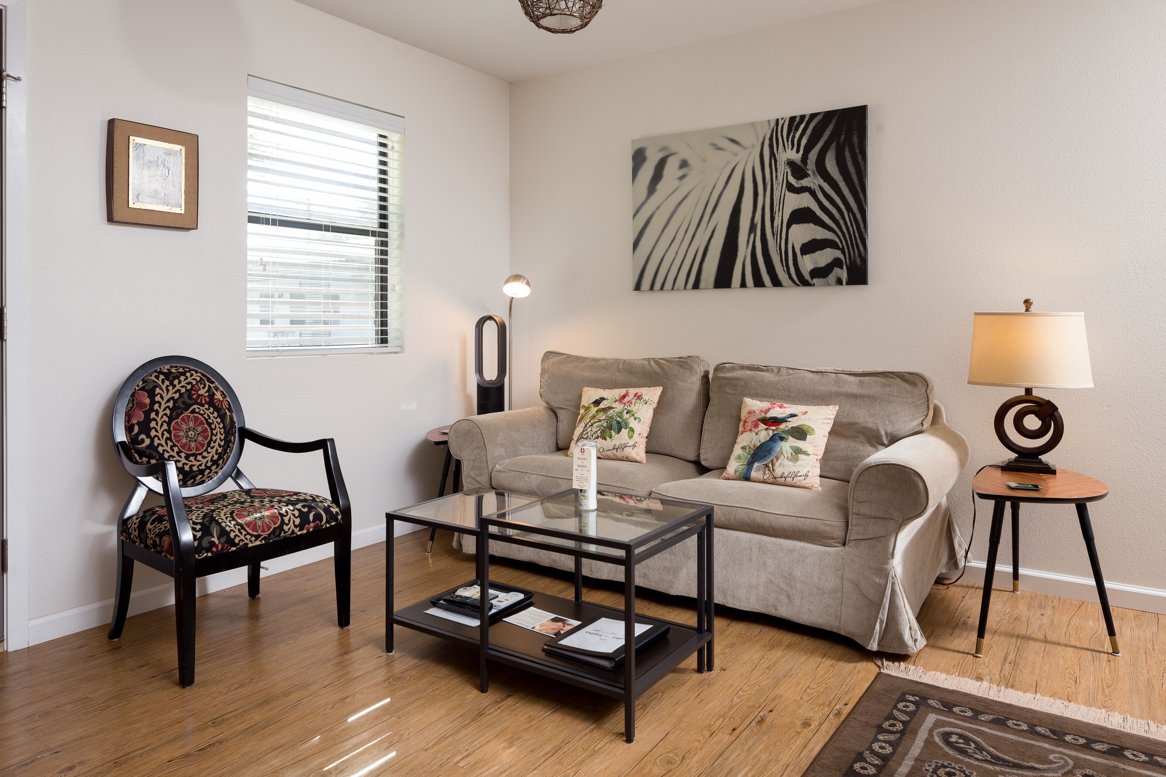 A living room with a sofa, a chair, a coffee table, a lamp, and a painting on the wall.