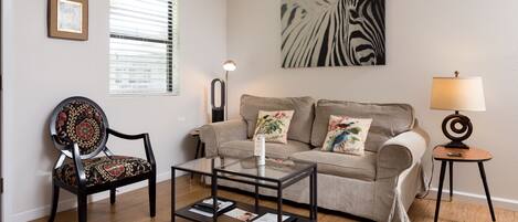 A living room with a sofa, a chair, a coffee table, a lamp, and a painting on the wall.