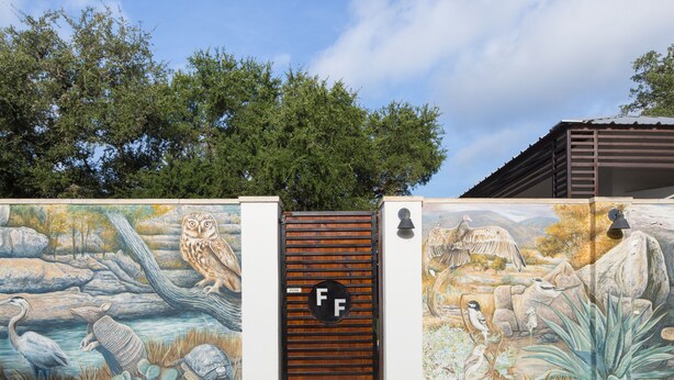 A mural of wildlife and a gate with the letters "FF". - Hotel Flora & Fauna (Wimberley)