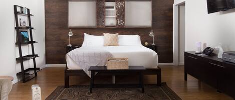 Une chambre à coucher avec un grand lit, une table de chevet, une lampe, un téléviseur, une bibliothèque et un tapis à motifs.