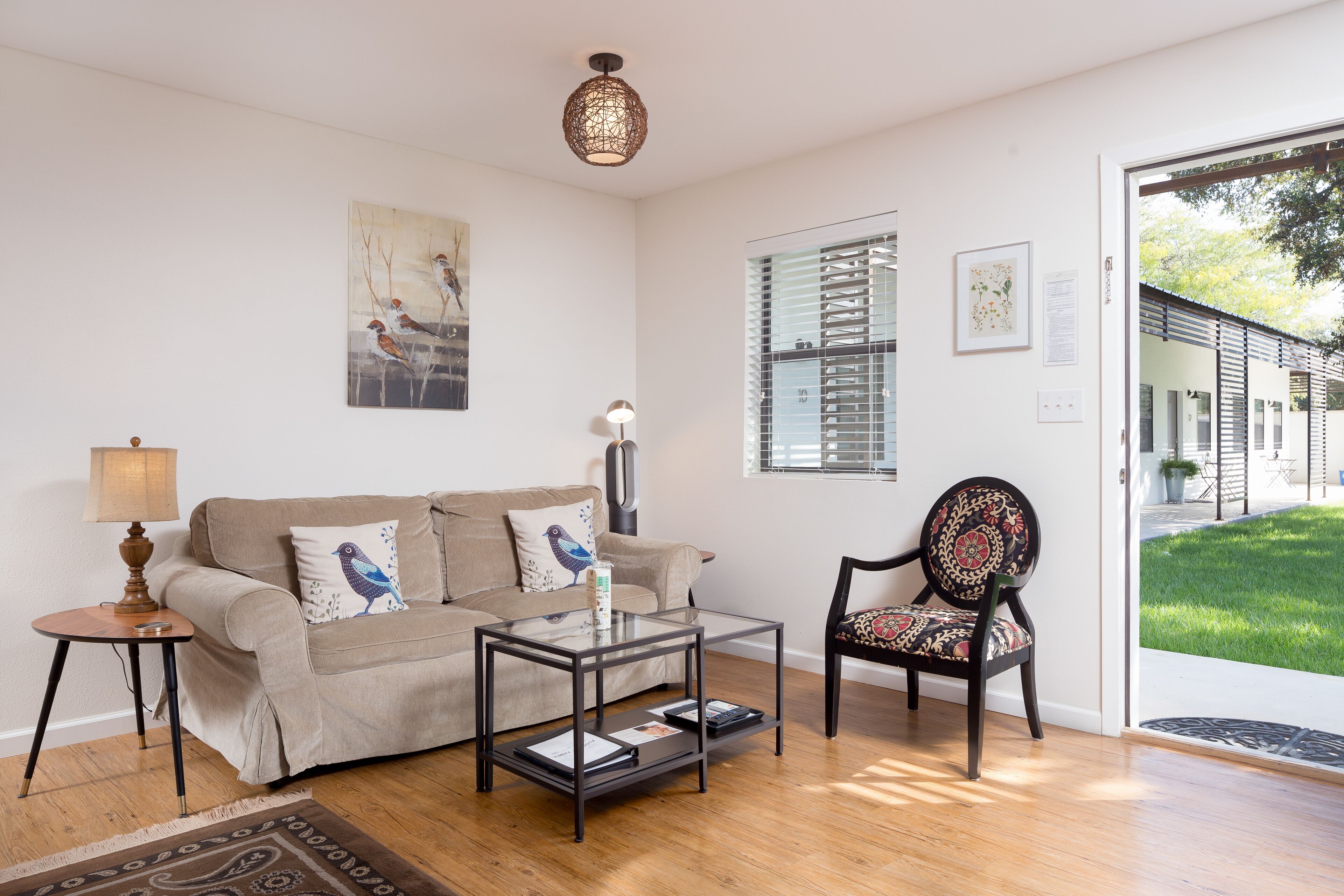 A living room with a sofa, a glass coffee table, a chair, a lamp, and a painting on the wall.