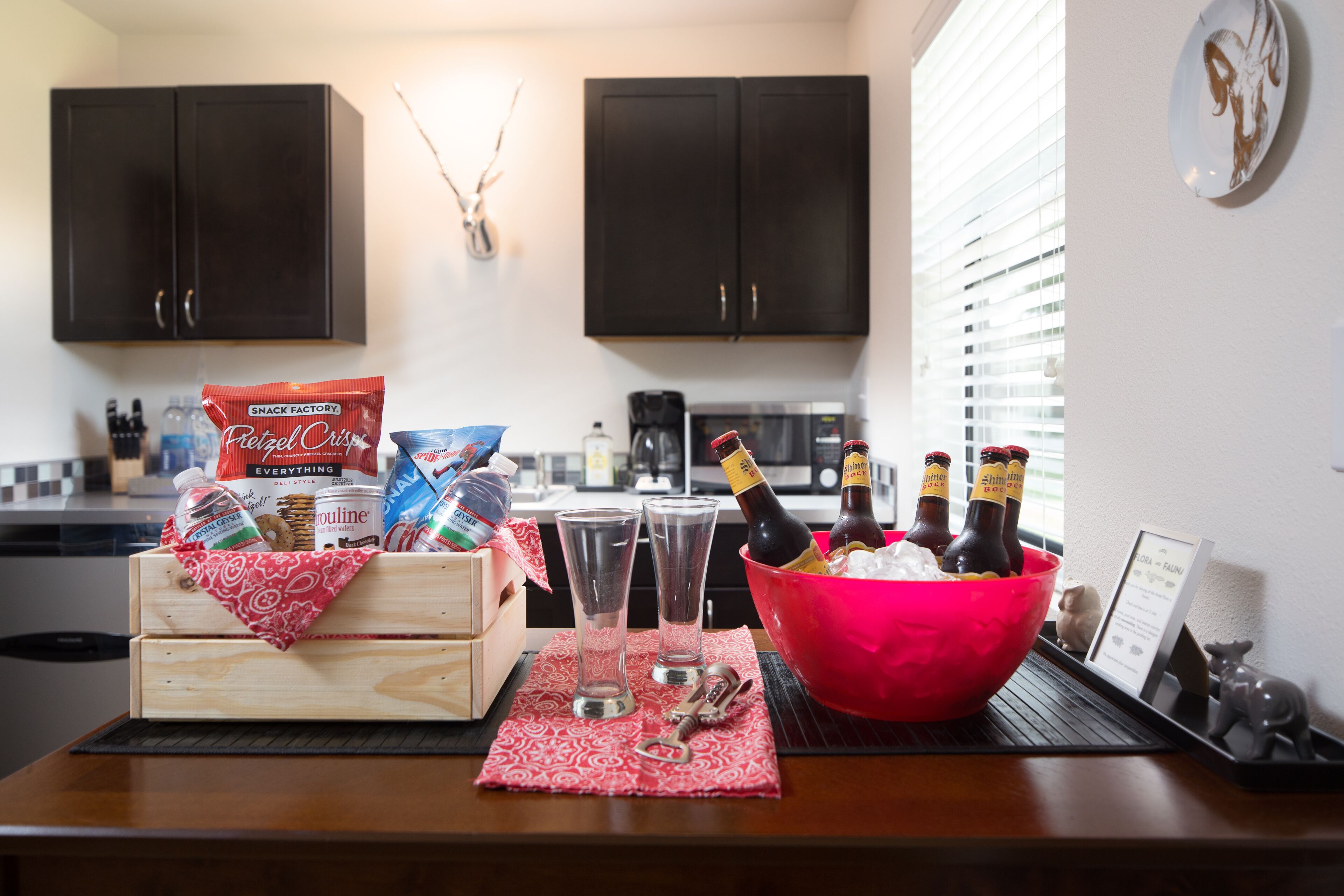 A kitchen counter with a wooden crate, a pink bowl, and bottles of beer.