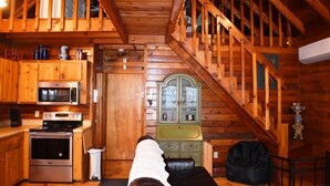 A cozy cabin interior with a kitchen, a dining area, and a staircase. - Deer Haven (Blue Ridge)