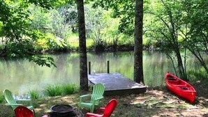 A lakeside campsite with a fire pit, two green chairs, and a red canoe. - Deer Haven (Blue Ridge)