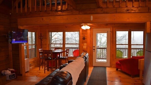 A cozy log cabin interior with a living room, dining area, and a balcony. - Deer Haven (Blue Ridge)