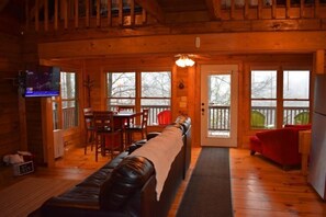 A cozy log cabin interior with a living room, dining area, and a balcony.