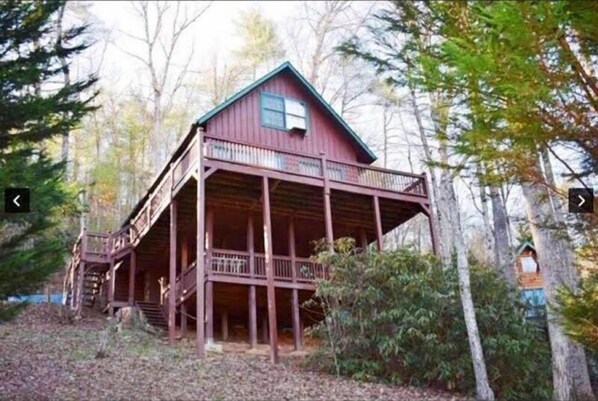 A wooden cabin with a balcony, surrounded by trees.