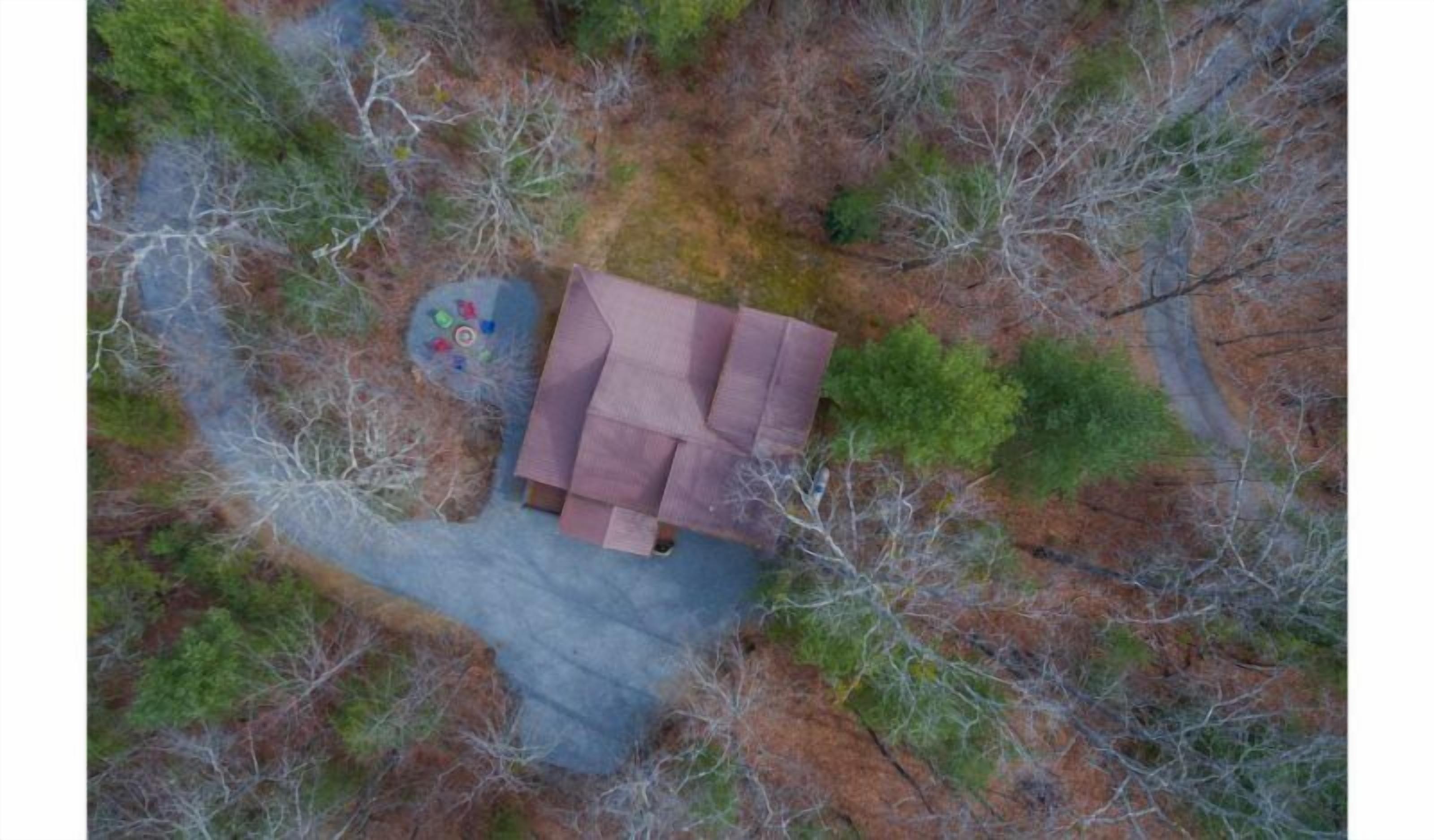An aerial view of a cabin surrounded by forest.
