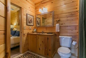 Ein Badezimmer in einer Holzhütte mit einem Holzkosmetikschrank, einer Toilette und einem Spiegel.