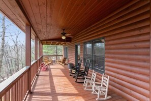 Eine Holzhütte mit Veranda, Schaukelstühlen und Blick auf Bäume.