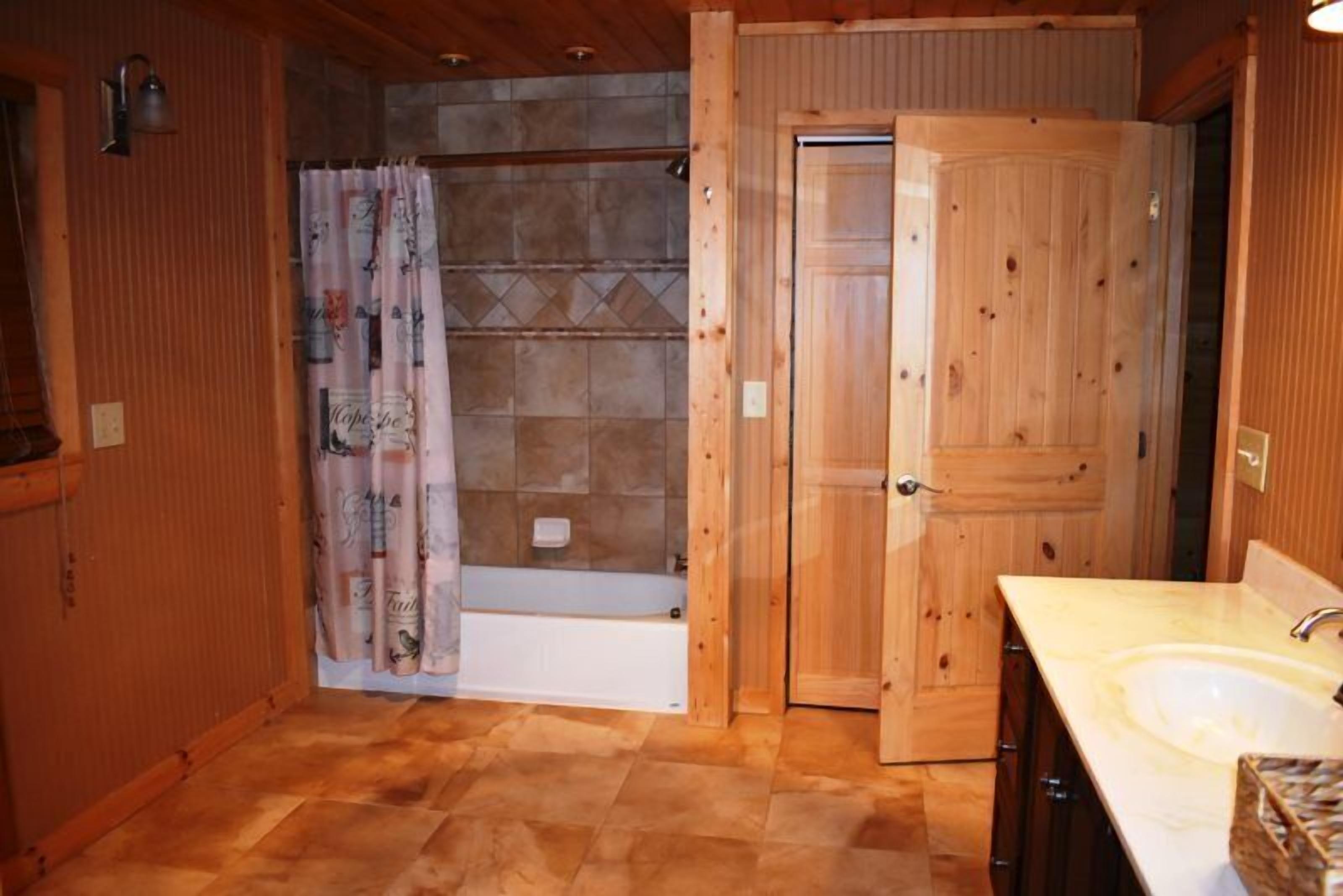 A bathroom with a bathtub, a shower curtain, wooden doors, and a sink.