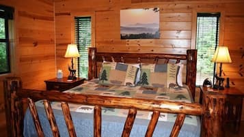 A wooden cabin bedroom with a bed, two nightstands, and a painting on the wall.