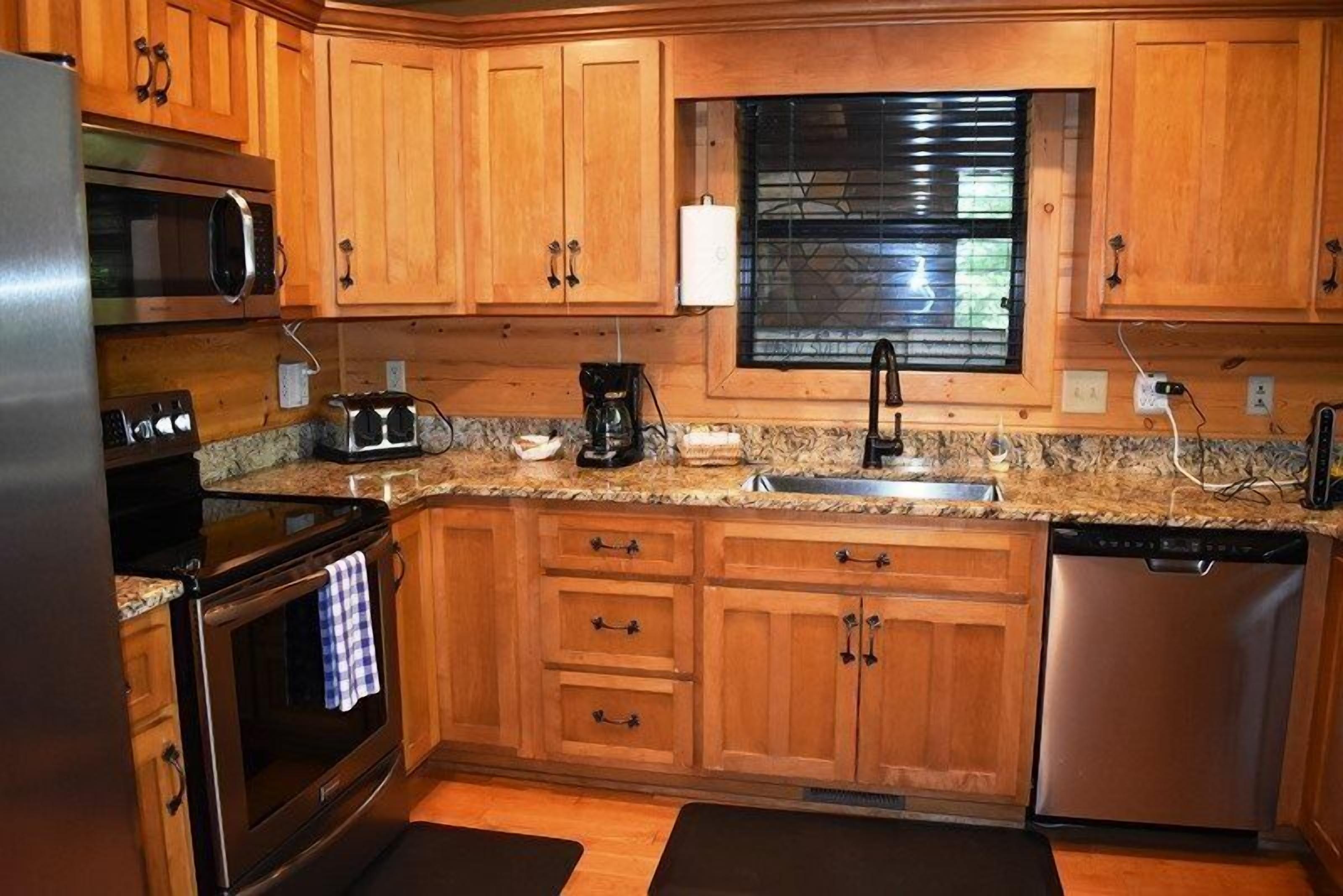 Una cucina con mobili in legno, un frigorifero in acciaio inossidabile, un forno a microonde, un tostapane, una macchina per il caffè e una lavastoviglie.