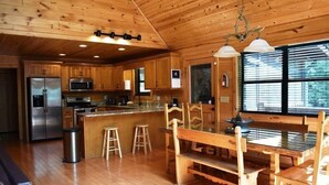 L’intérieur d’un chalet en bois comprend une cuisine, un coin repas et une grande fenêtre.