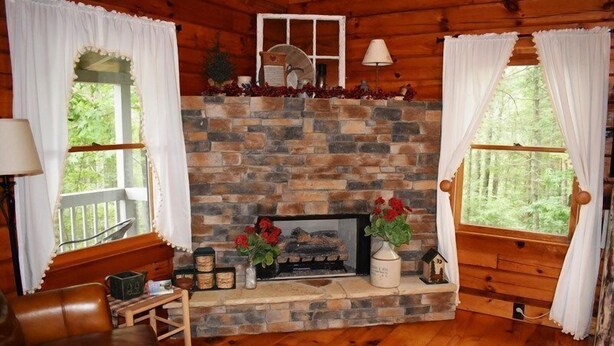 A cozy cabin interior with a stone fireplace, wooden walls, and a comfortable seating area. - Serenity Summit (Blue Ridge)