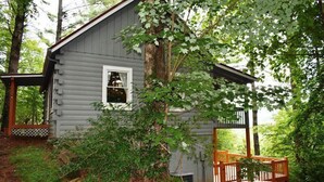 A rustic cabin with a wooden deck and a bench, surrounded by dense greenery. - Serenity Summit (Blue Ridge)