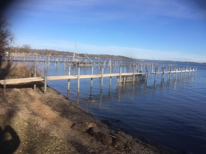 A wooden dock extending into a calm body of water, surrounded by a grassy area and a clear sky.
