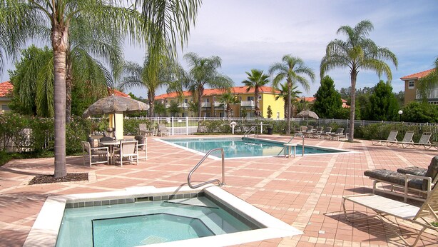 A swimming pool area with lounge chairs and a hot tub.