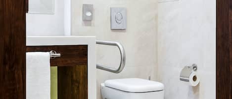 Une salle de bain moderne équipée de toilettes, d’un porte-serviettes et d’un distributeur de serviettes en papier.
